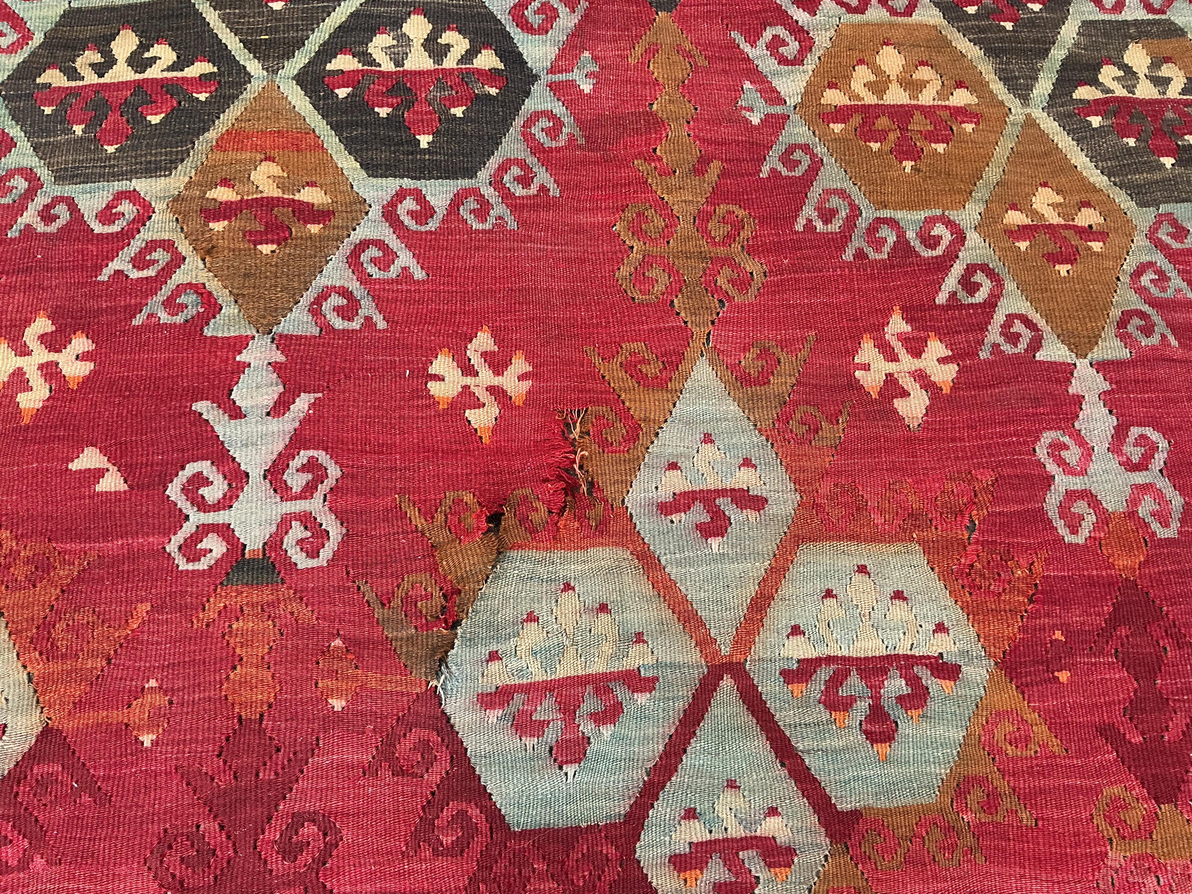 A Turkish Anatolian Kilim polychrome flatweave carpet, woven with geometric lozenges, on a pink field, 350 x 273cm